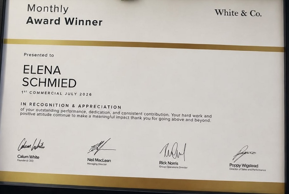 Urkunde von White & Co: Monthly Award Winner, 1st Commercial, Juli 2026, ausgestellt auf Elena Schmied, unterzeichnet von Calum White, Neil MacLean, Rick Norris und Poppy Wigstead